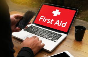 man looking up "First Aid" on laptop