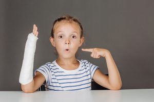 child pointing at her arm cast