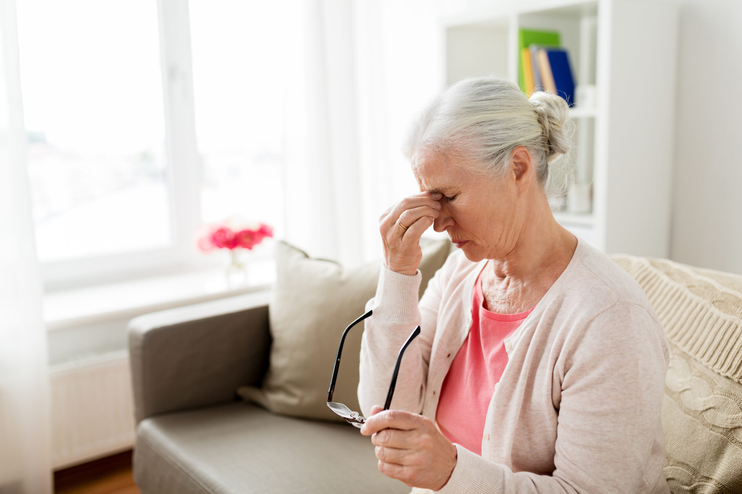 An elderly woman rubbing her eyes and having vision problems