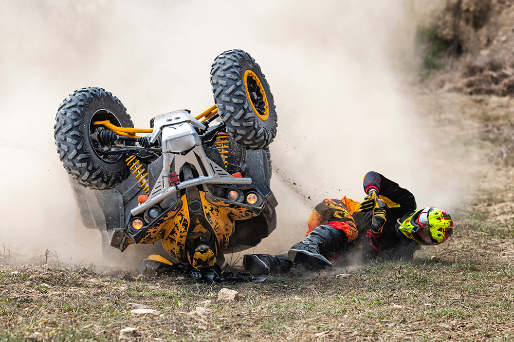 Quadbike rider falling off vehicle mid-crash, creating dust cloud on dirt terrain
